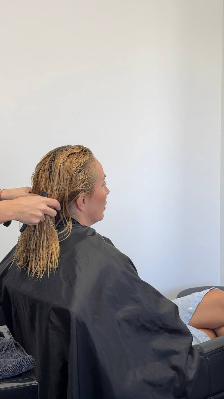 Mila checking the condition of a client's hair before choosing the treatment