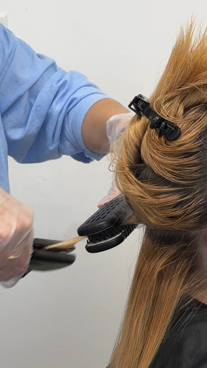 A thin section of hair passing through the iron during a smoothing service